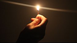 Una mano sostiene un cerillo encendido