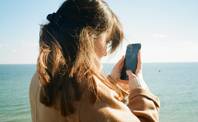 Una joven mira su teléfono de cerca. Foto: Unsplash, minusculemarie