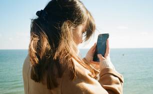 Una joven mira su teléfono de cerca. Foto: Unsplash, minusculemarie